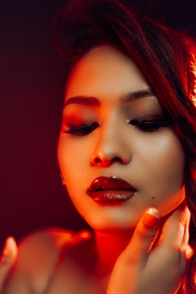 Stunning close-up portrait with warm red lighting highlighting a woman's face.